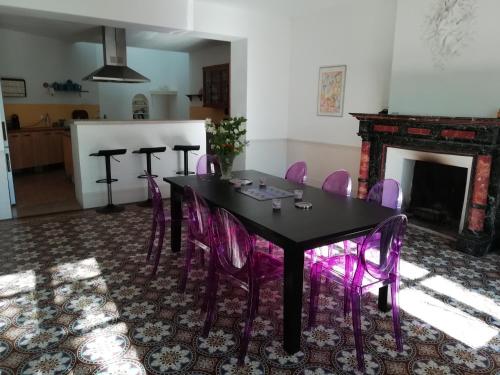 une salle à manger avec une table noire et des chaises violettes dans l'établissement Les Colonnades, à Moussan