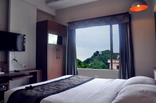 a bedroom with a bed and a large window at Hotel Sheela Shree Plaza in Jhānsi