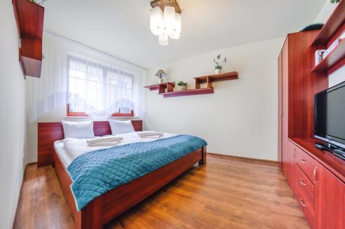 a bedroom with a bed and a flat screen tv at Apartamenty Sun & Snow Willa Teresa in Krynica Morska