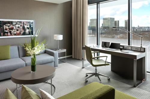 a living room with a couch and a desk with a computer at Pullman Paris Centre - Bercy in Paris