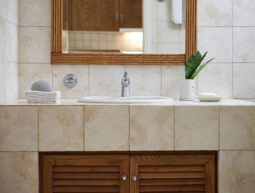 un bancone del bagno con lavandino e specchio di Plaka Sea Front Residence a Eloúnda