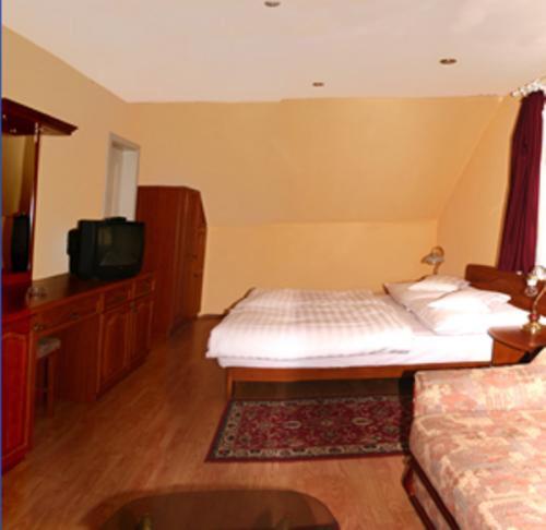 a living room with a bed and a tv at Szieszta Panzió in Sárvár