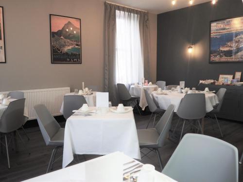jadalnia z białymi stołami i krzesłami oraz oknem w obiekcie Seaview House Bed and Breakfast w mieście Larne