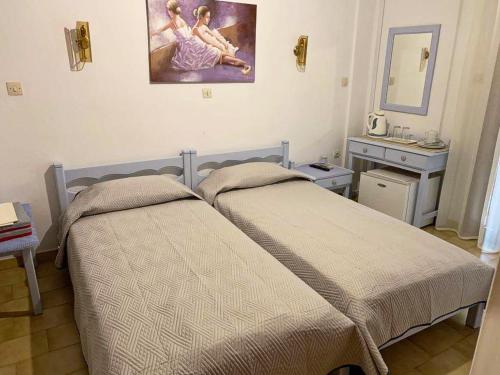 een slaapkamer met 2 bedden en een schilderij aan de muur bij Sunshine Pension in Pythagoreio