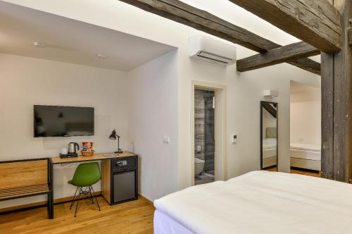 a bedroom with a bed and a desk with a television at Hotel Garden Court in Prague