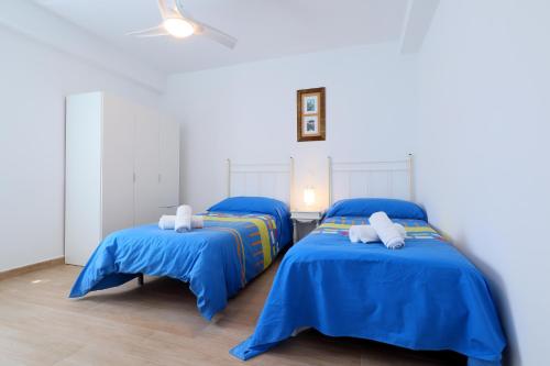 two beds in a room with blue sheets at Rosas en la Balconada & Apartment with Parking in Córdoba Historic Center in Córdoba