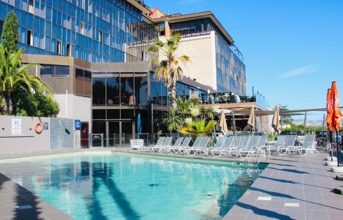 une piscine avec des chaises et un bâtiment dans l'établissement Novotel Marseille Vieux Port, à Marseille