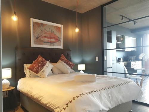 a bedroom with a bed with white sheets and pillows at Wex 1 Apartments in Cape Town