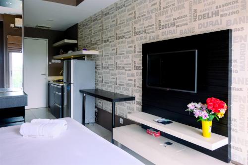 a bedroom with a tv and a brick wall at Comfy Studio Apartment @ Skylounge Tamansari By Travelio in Tangerang
