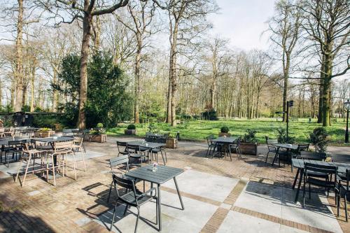 a patio with tables and chairs in a park at Landgoed Oud Poelgeest - Leiden in Oegstgeest