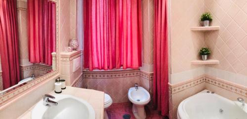 bagno con tende rosse, servizi igienici e lavandino di Colosseo Room a Roma