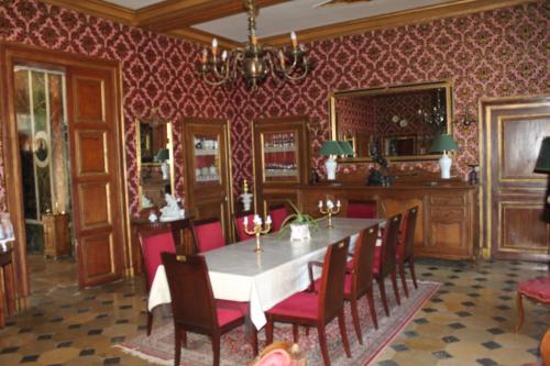 Deux-ChaisesにあるChateau de Longevilleの赤い壁紙とテーブル付きのダイニングルーム