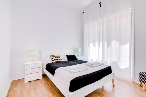 a white bedroom with a bed and a window at À da Avó -The Guesthouse in Faro