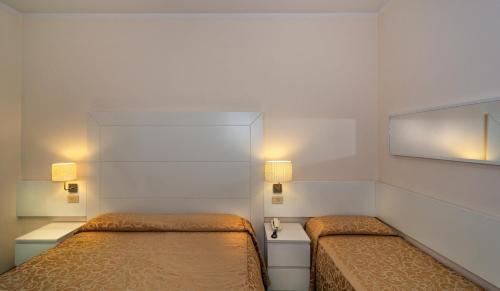 a small bedroom with two beds and two lamps at Hotel Esplanade in Marina di Pietrasanta