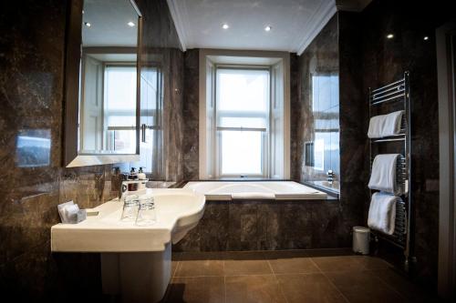 uma casa de banho com um lavatório e uma banheira em Seamill Hydro Hotel em Seamill