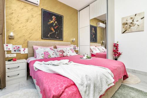 een slaapkamer met een roze bed en een spiegel bij Apartment 4You in Budva