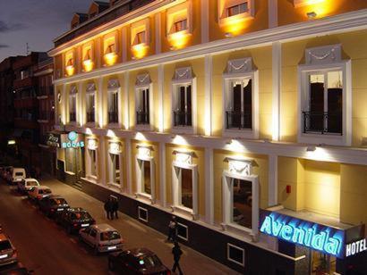 een groot gebouw met auto's geparkeerd voor het bij Hotel Avenida Leganés in Leganés