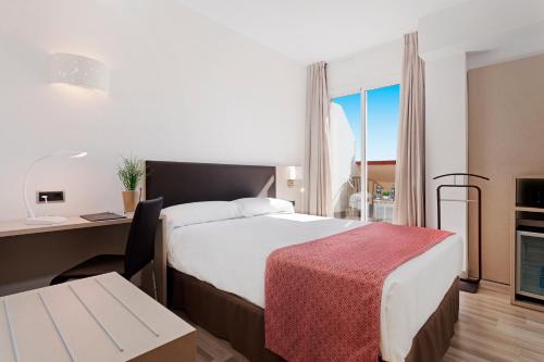 Habitación de hotel con cama, escritorio y mesa. en Catalonia Hispalis, en Sevilla