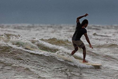 a man riding a wave on a surfboard in the ocean at Tanjung Inn in Kuantan