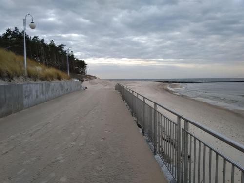 a sandy beach with a fence next to the ocean at Apartamenty Bulwar Nadmorski, Rowy in Rowy