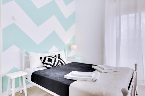 a white bedroom with a bed with a black blanket at À da Avó -The Guesthouse in Faro