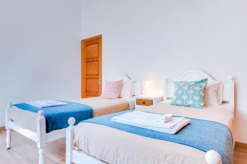 two beds in a room with white walls at À da Avó -The Guesthouse in Faro