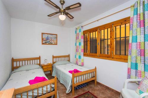 sypialnia z dwoma łóżkami i wentylatorem sufitowym w obiekcie CH Vista Alegre Rocio del Mar w mieście Torrevieja