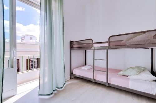 a bedroom with bunk beds and a large window at À da Avó -The Guesthouse in Faro