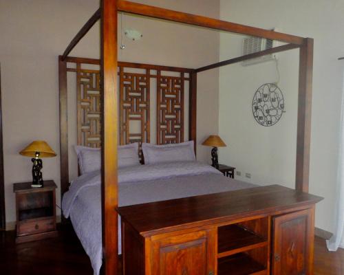 a bedroom with a bed with a wooden frame and a mirror at Popa Paradise Beach Resort in Buena Vista