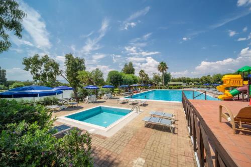 a pool with chairs and umbrellas at a resort at TH Marina di Sibari - Baia Degli Achei Village in Marina di Sibari