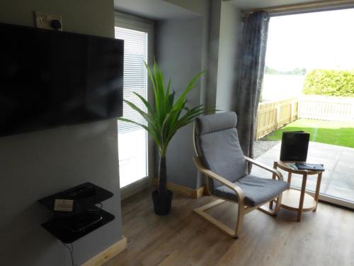 a living room with a chair and a flat screen tv at Auchendennan Farm Self Catering Cottages in Balloch