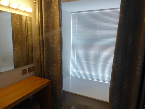 a window with blinds and a mirror in a room at Auchendennan Farm Self Catering Cottages in Balloch
