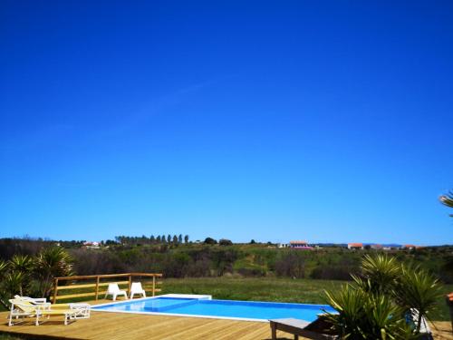 a swimming pool with two chairs and a wooden deck at Quinta de Moledos in Aljezur