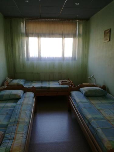 3 camas en una habitación con ventana en Brīvdienas, en Alūksne
