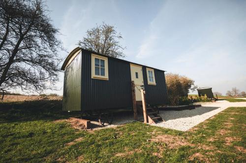ein schwarzes und gelbes winziges Haus auf einem Feld in der Unterkunft Avon Riverside Glamping in Warwick
