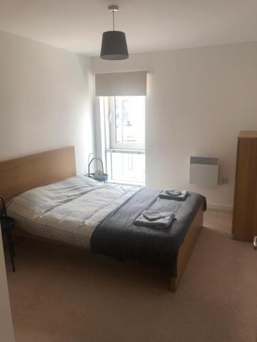 a bed in a bedroom with a large window at Quayside Apartment in Cardiff Bay in Cardiff