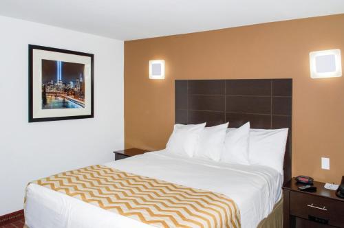 a hotel room with a large bed with white sheets at Travelodge by Wyndham Manhasset in Manhasset