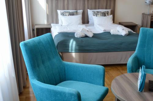 a bedroom with a bed and two chairs and a table at Kosmopolita Apartments in Kraków