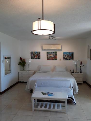 Un dormitorio con una gran cama blanca y una lámpara de araña. en Point Village Negril, en Negril