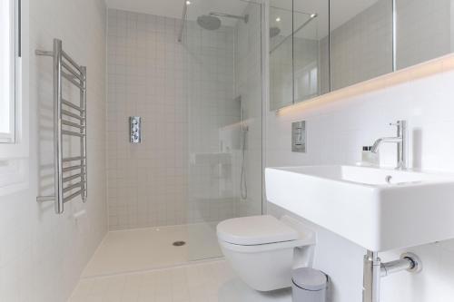 a white bathroom with a shower and a toilet and a sink at StayInn Farringdon in London