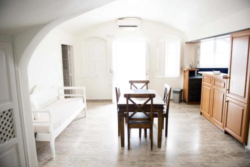 a kitchen with a table, chairs and a refrigerator at Captain John Houses Oia in Oia