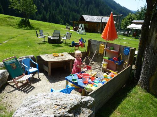 a little girl playing in a sandbox in a backyard at Residence Bannwald in Valle Di Casies