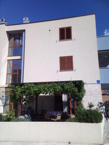 a white building with windows and plants in front of it at Apartman Edi in Nin