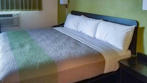 a bed with a multicolored blanket and white pillows at Motel 6-Burlington, WA in Burlington