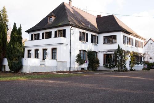 une maison blanche avec un toit noir dans une rue dans l'établissement Hotel restaurant au gourmet, à Drusenheim