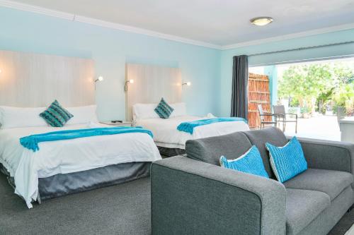 Habitación de hotel con 2 camas y sofá en AL-BEIT LODGE en Puerto Elizabeth