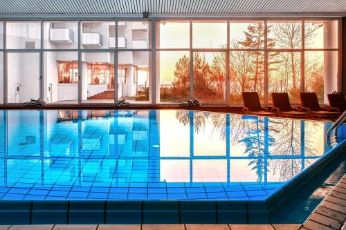 a large swimming pool with chairs in a building at Vienna House by Wyndham Amber Baltic Miedzyzdroje in Międzyzdroje