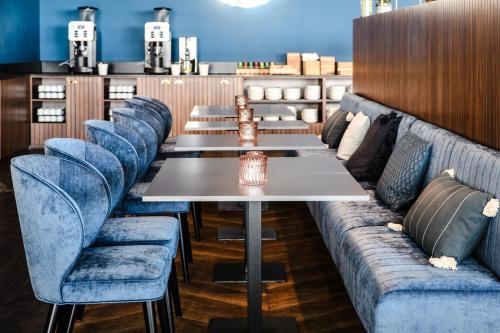 a row of tables and blue chairs in a restaurant at Vienna House by Wyndham Amber Baltic Miedzyzdroje in Międzyzdroje