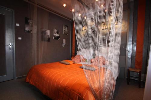 a bedroom with an orange bed with a curtain at Hotel Le Rocher Blanc in Albaret-Sainte-Marie