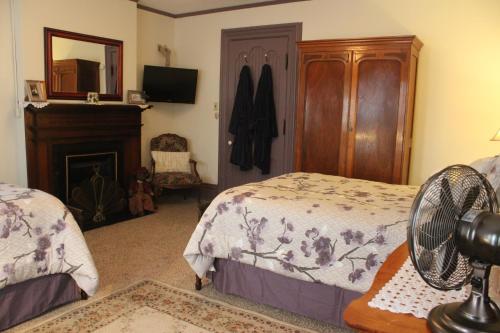 a bedroom with two beds and a fan and a fireplace at Spencer House Bed & Breakfast in Erie